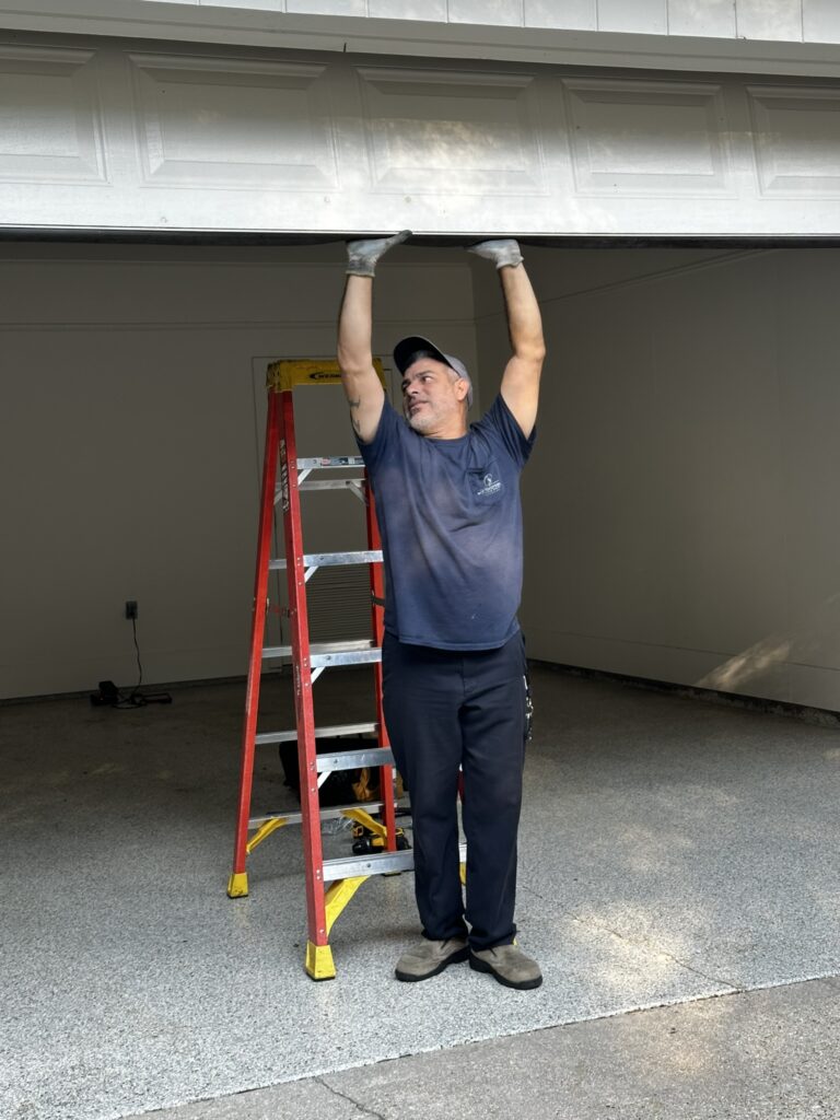 Homeowner inspecting a garage door making grinding noise during routine maintenance