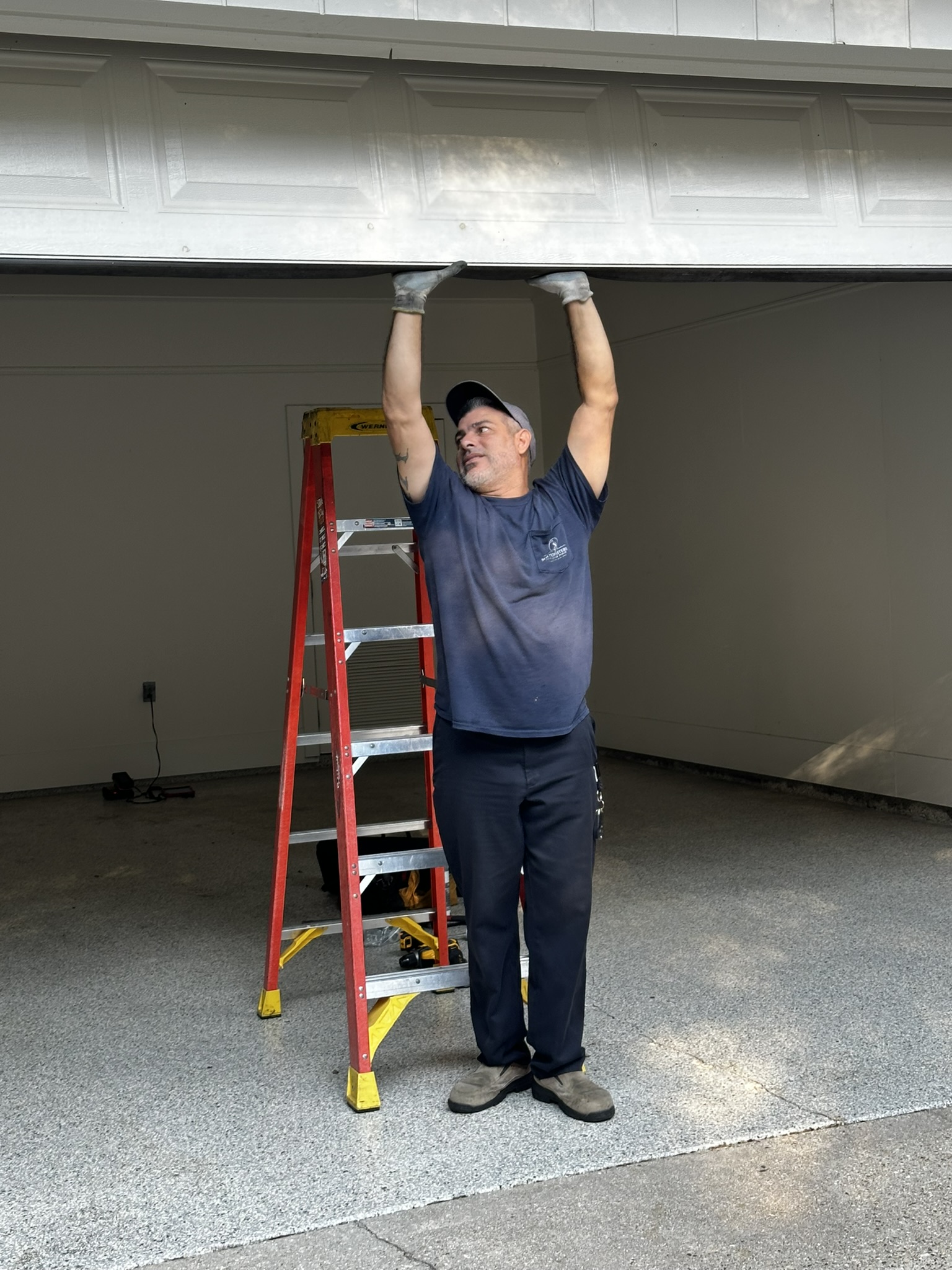 Homeowner inspecting a garage door making grinding noise during routine maintenance